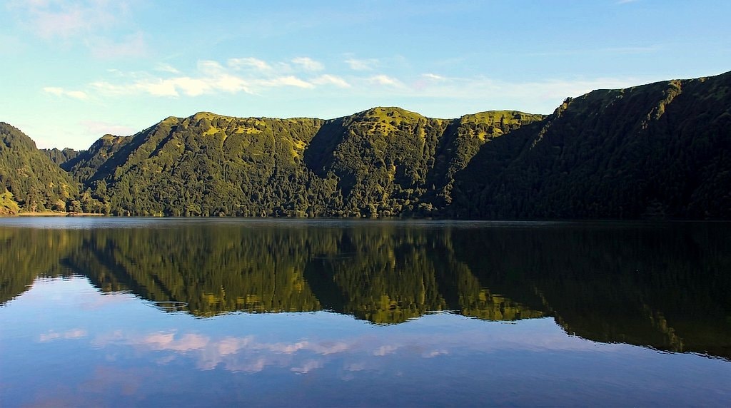 Calm crater lake reflecting green mountains in Sete Cidades, São Miguel