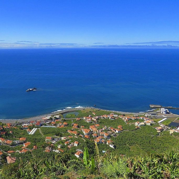 View from an open-top jeep over a Madeira coastal village and banana plantations.