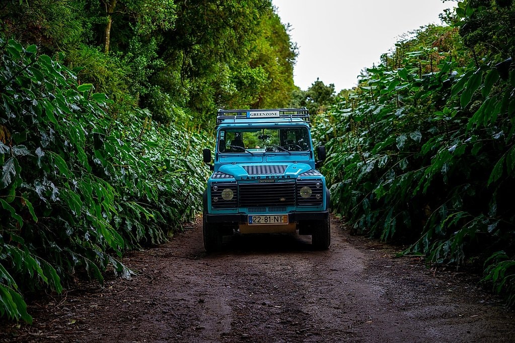 Jeep tour vehicle on a narrow dirt track through dense green forest on the way to Nordeste