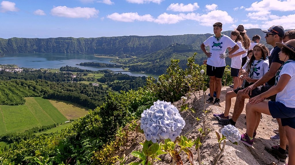 Hikers pause at a hydrangea-lined viewpoint over Sete Cidades' twin crater lakes and green valley floor