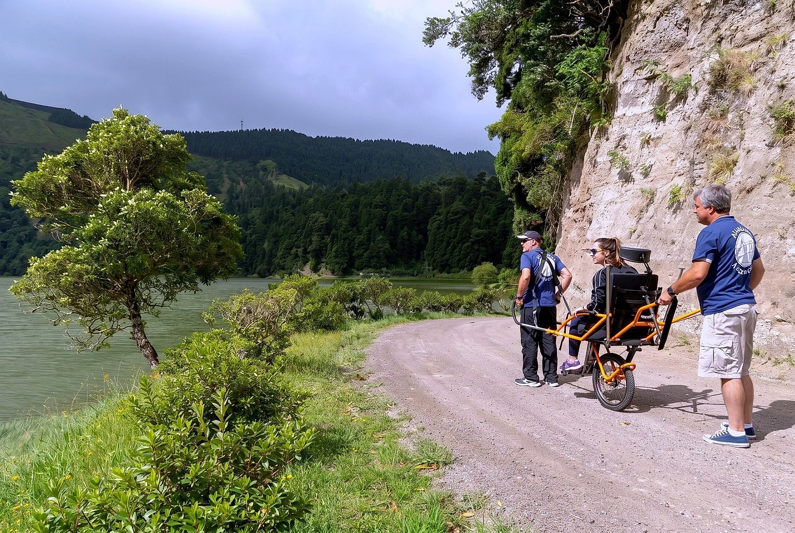 Guides pause the Joelette chair so the rider can take in cliffside views over Sete Cidades lake.
