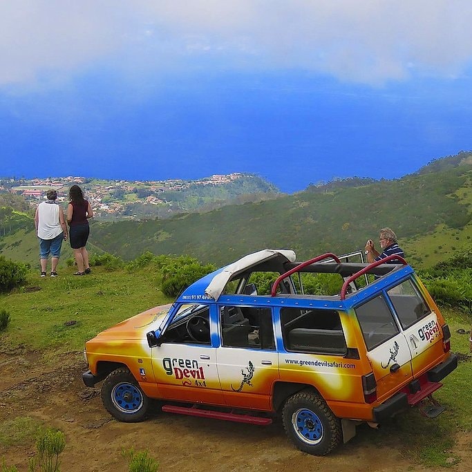 Tourists admiring the coastal view beside a parked Green Devil 4x4 jeep, Madeira.