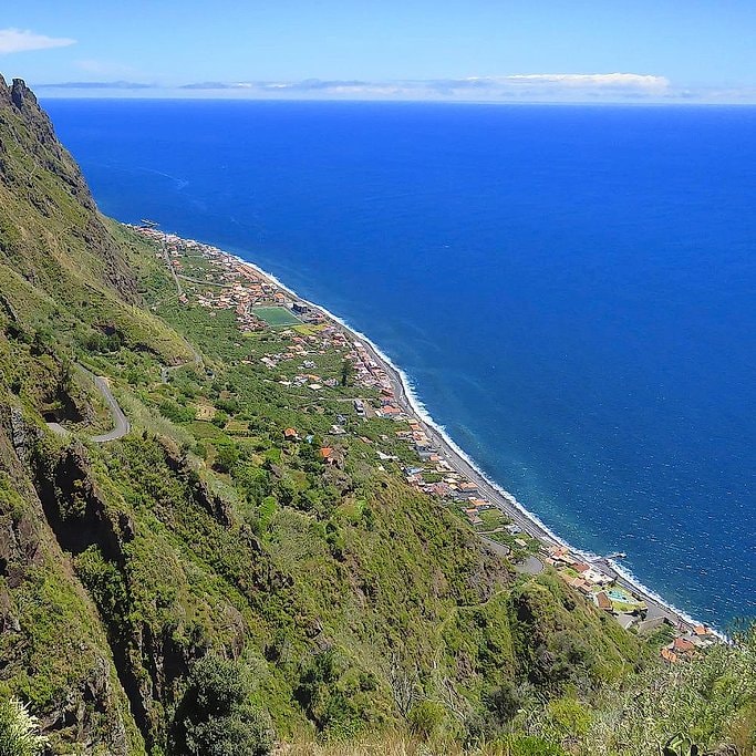 Aerial view along Madeira's southwest coast, a village squeezed between steep cliffs and the sea.