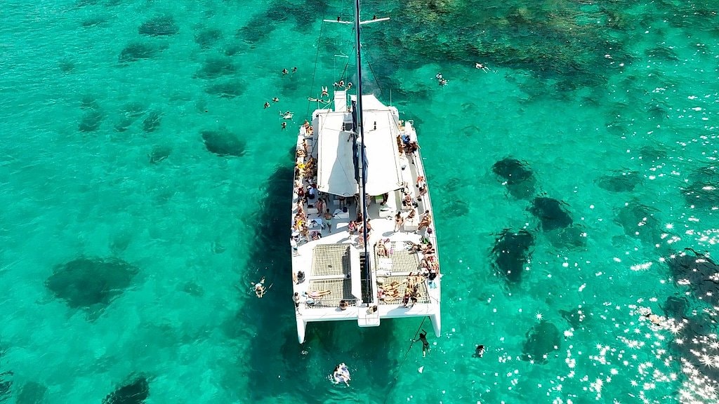 Aerial view of the catamaran anchored over a reef with swimmers scattered around.