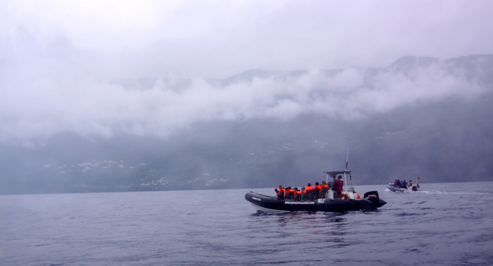 A small whale watching boat on open water off the Azores with passengers watching the sea