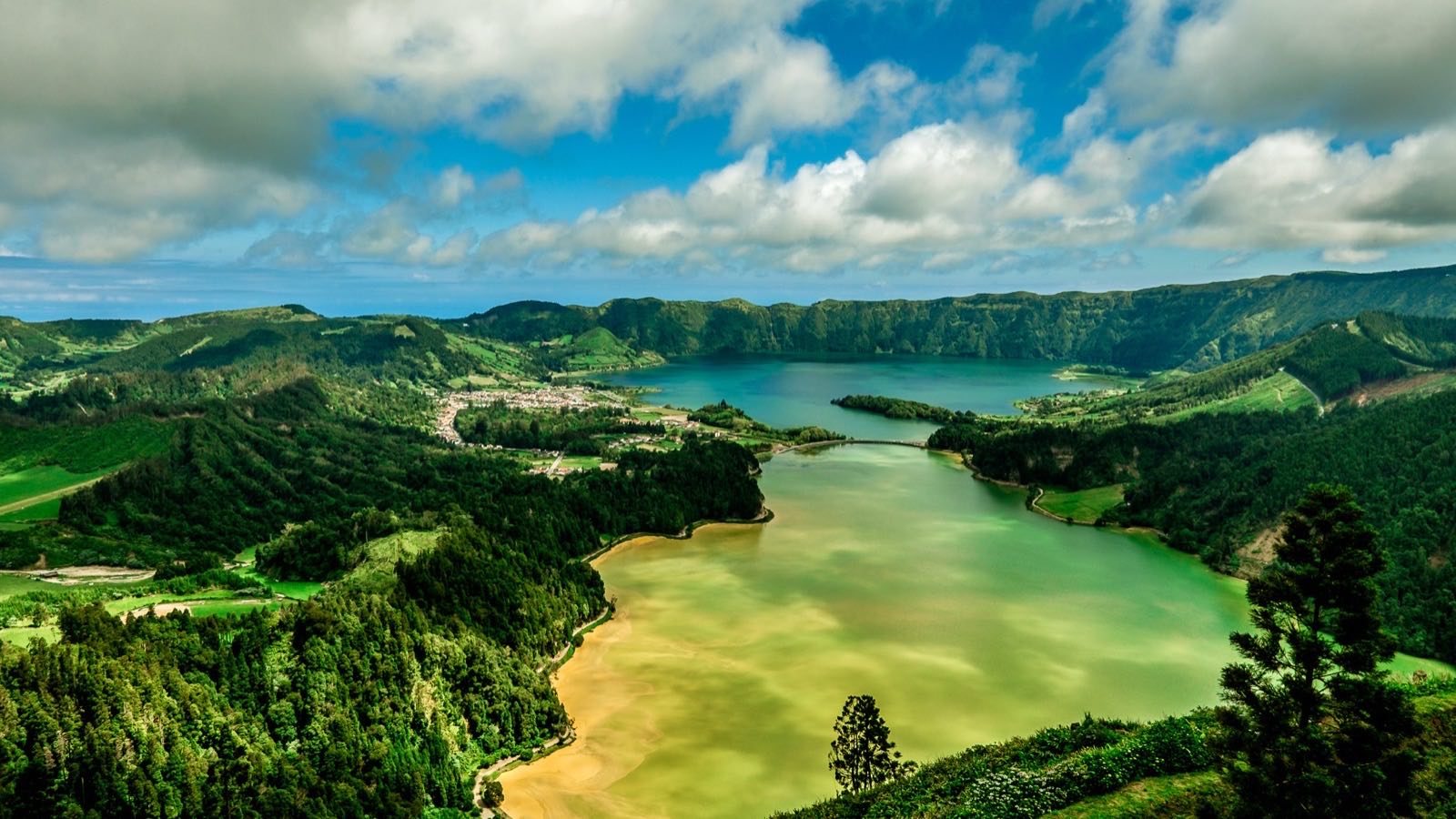 アゾレス諸島Sao Miguel島にあるSete Cidadesの緑色のカルデラ湖が、険しい森に覆われた斜面に囲まれ、柔らかな空の下に広がる様子。