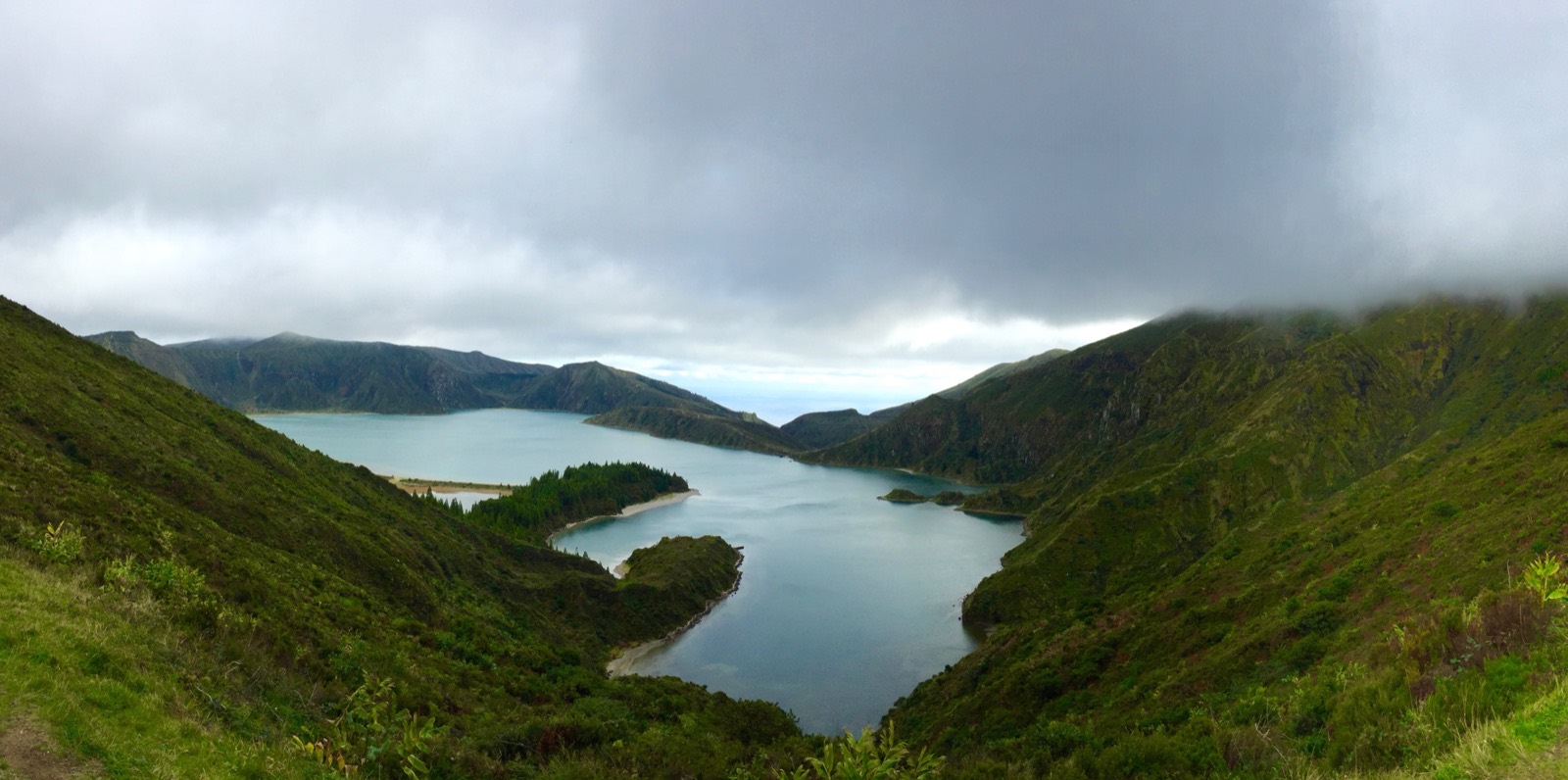 بحيرة فوهة Lagoa do Fogo على جزيرة Sao Miguel في الأزور، يلتف ساحلها الفاتح أسفل منحدرات خضراء شديدة الانحدار